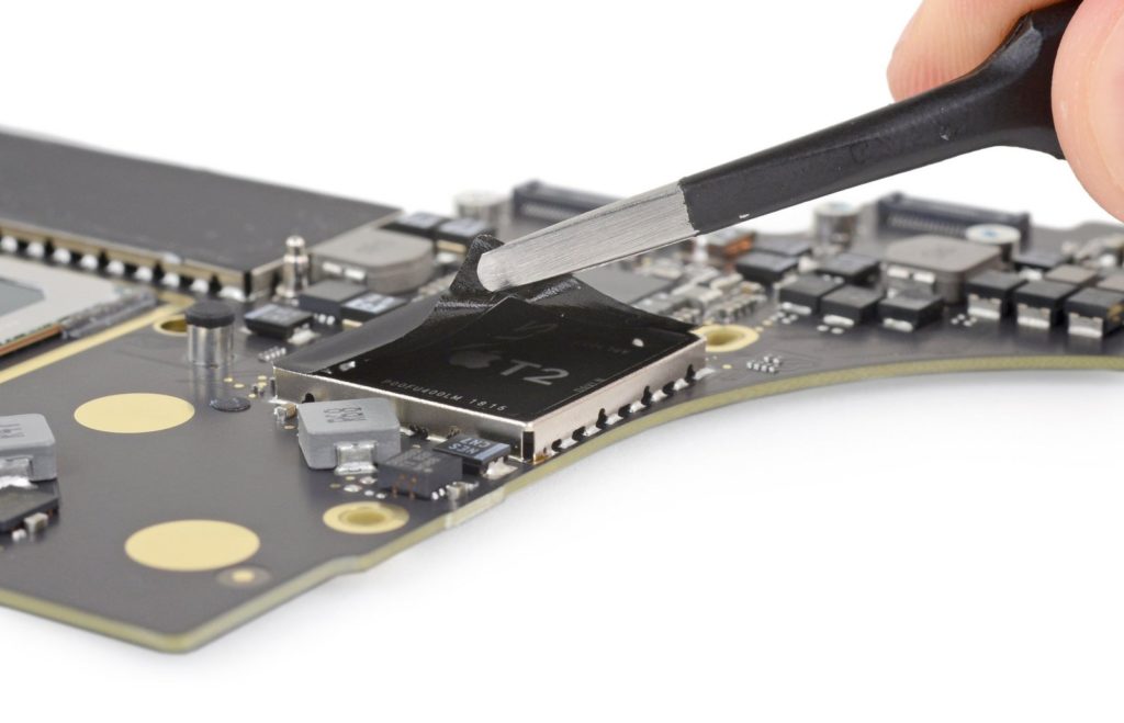 Пинцет, раскрывающий чип безопасности T2 на логической плате MacBook Pro.
